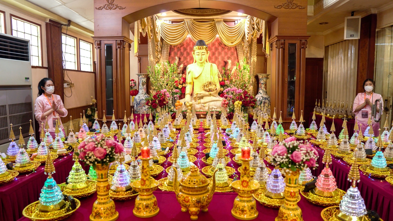 A table with many candles and a statue of a buddha

Description automatically generated