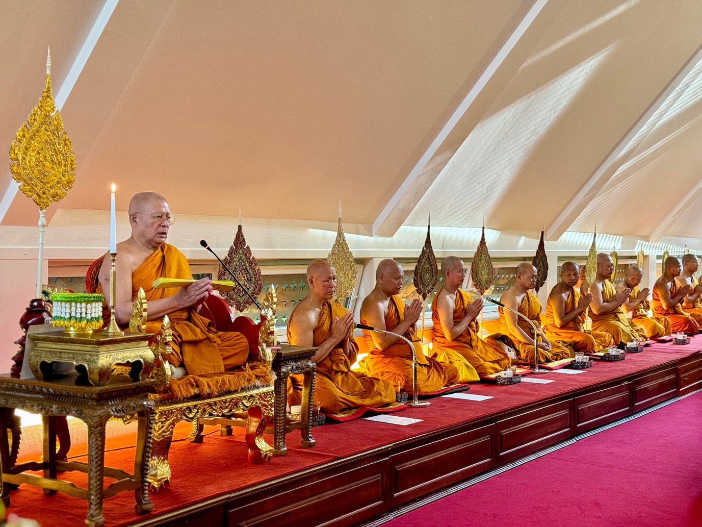 A group of men sitting on a long row of gold objectsDescription automatically generated